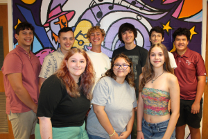 students posing in front of mural